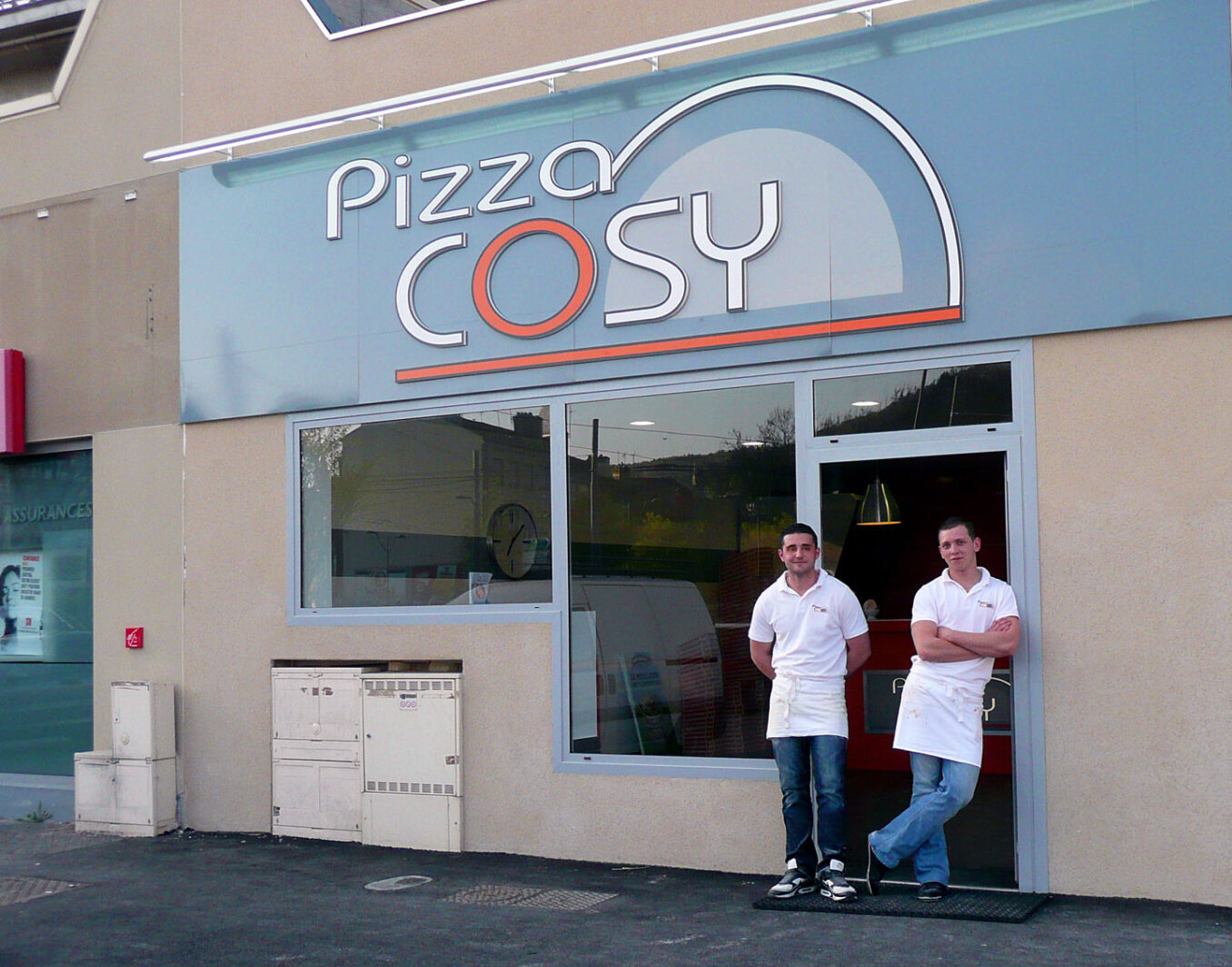 Photo du premier pizza cosy avec les deux associés devant la porte.