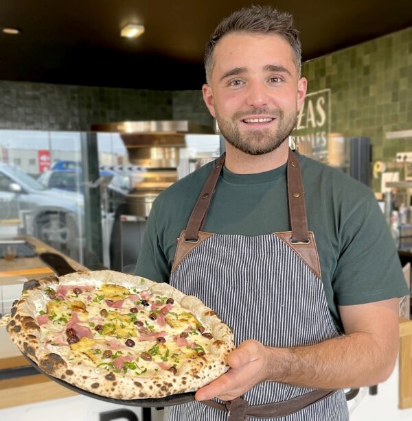 Pizzaiolo présentant une pizza jambon de Pizza cosy